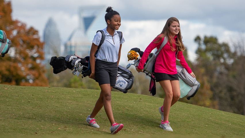 Two young girls walking on a golf course